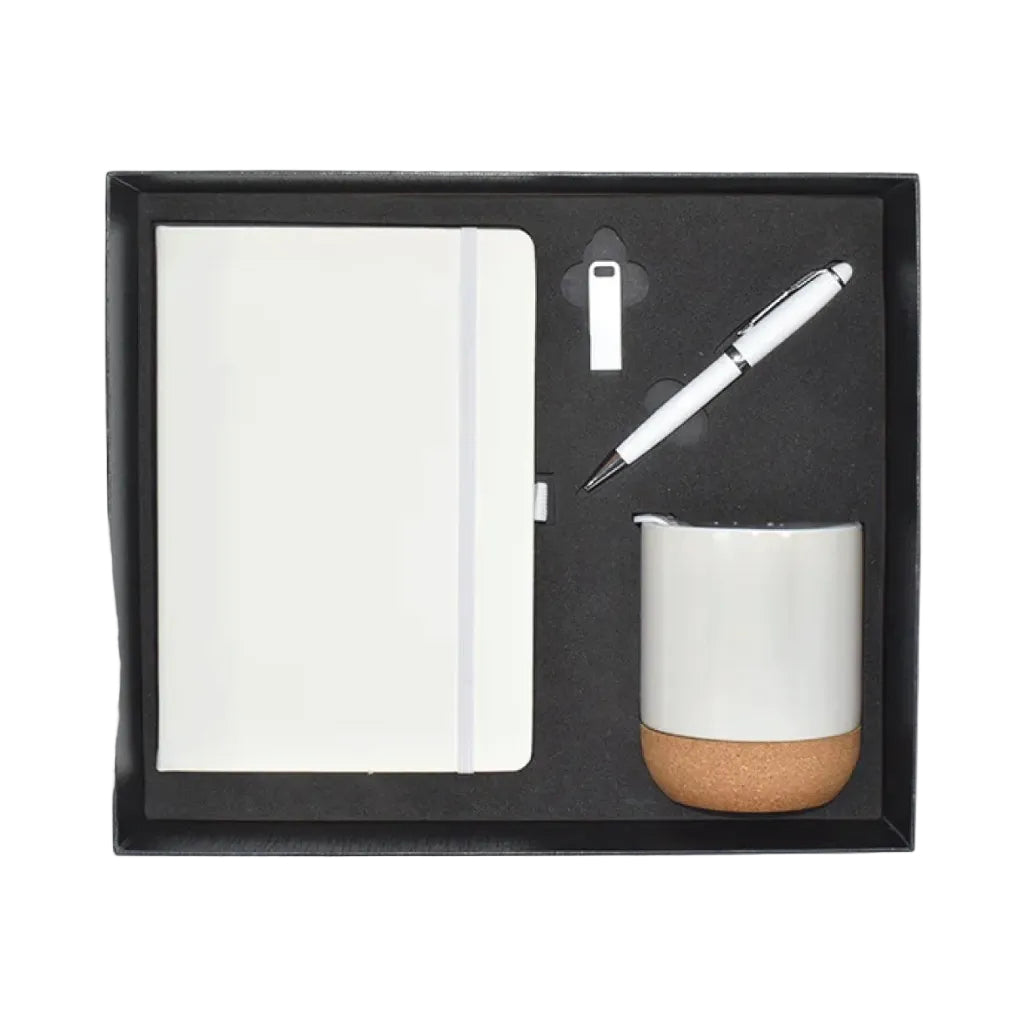 A black gift box containing a white notebook, a white pen, and a white cup with a cork base, arranged on a black foam insert.
